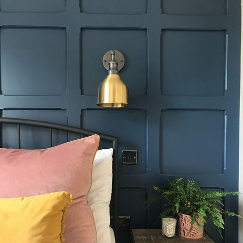 A brass wall light in a colourful bedroom