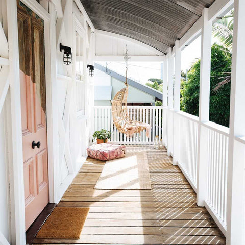 A wooden rustic house balcony with pink highlights and seating