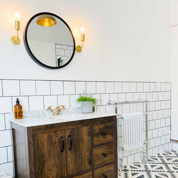 Tiled bathroom with circular mirror and wood cabinet