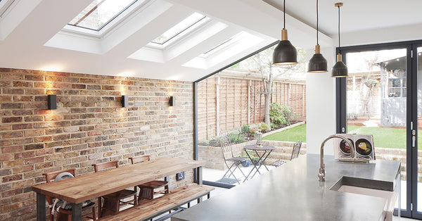 Modern kitchen diner interior with a brick wall and a trio of industrial pendant lights
