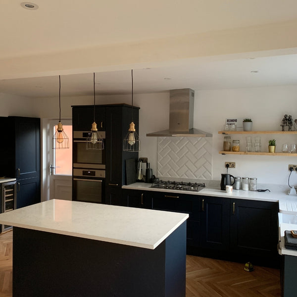 A modern kitchen interior with dark cupboards and white work surfaces