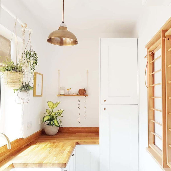 A bright kitchen with plants and a brass pendant