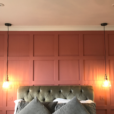 A bedroom with a pink wall and hanging lights