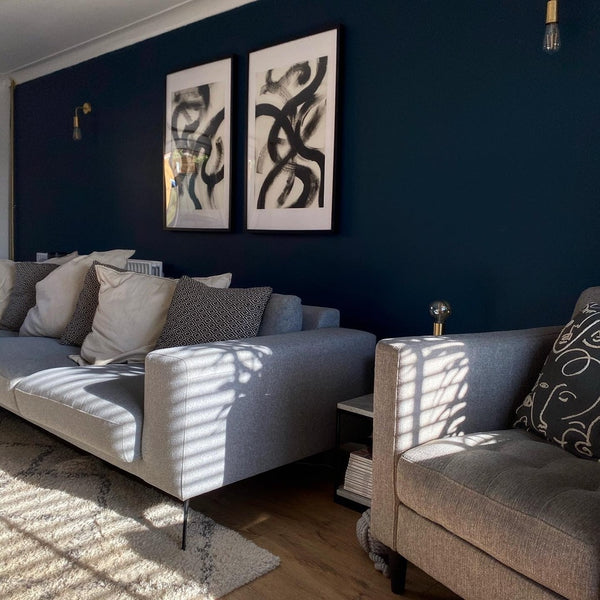 A living room with navy blue walls and black and white art