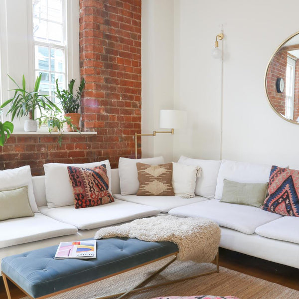 An L-shaped sofa complements by a stool and floor cushion 