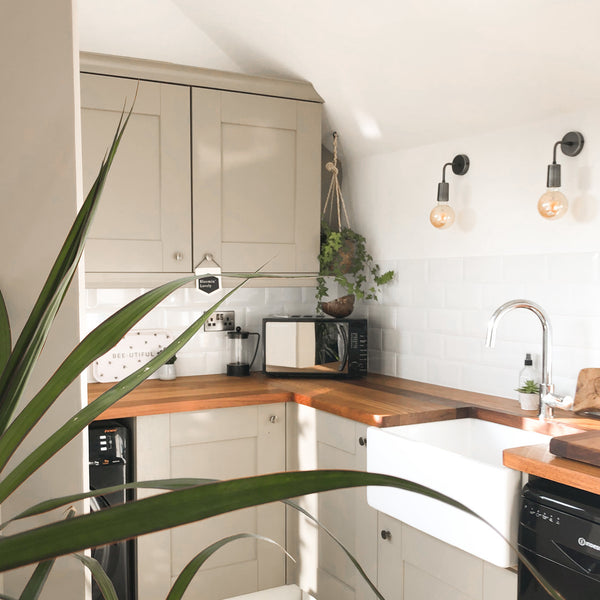 A small but open kitchen with wall lights 