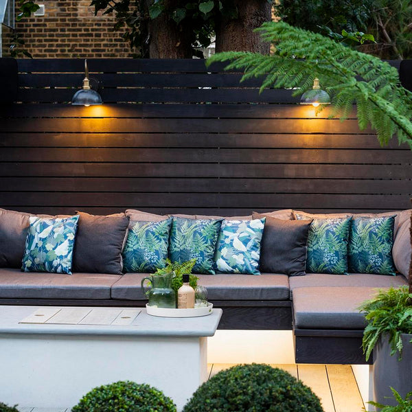 A modern garden interior with seating, cushions and industrial lights