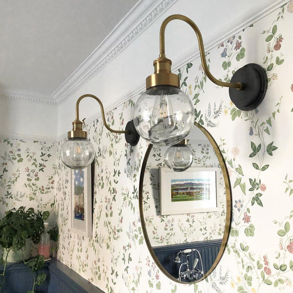 Vintage swan neck wall lights with glass shades in a floral bathroom 