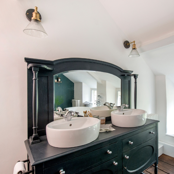 Glass funnel lights on either side of a vintage mirror and sink set-up