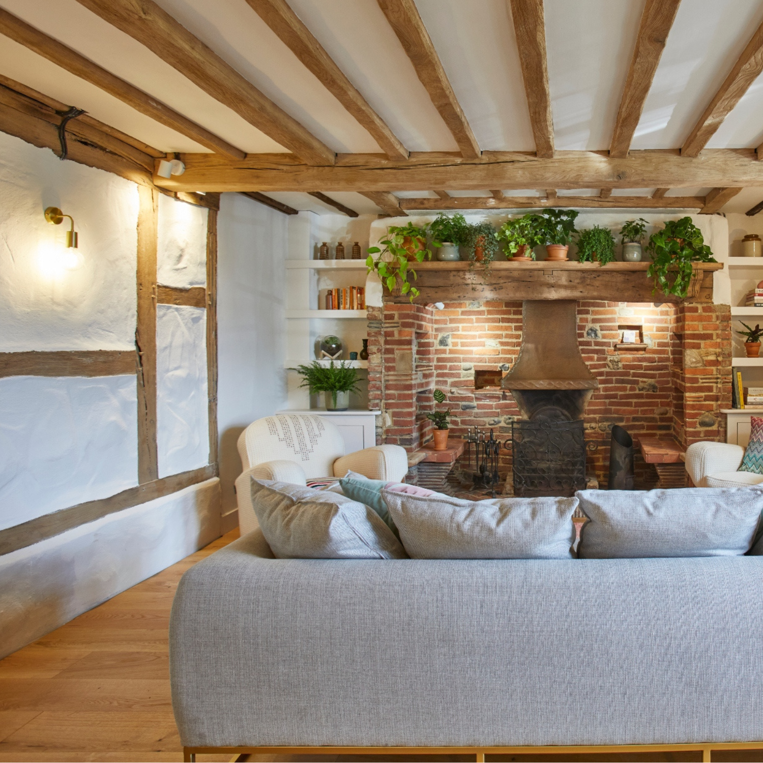 An Edison wall light in a cottage living room with wooden beams and fireplace