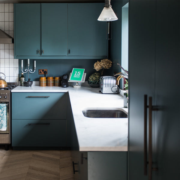 A modern kitchen with green cupboards and glass lighting by Industville