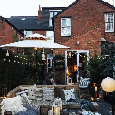 A bohemian garden with lights and outdoor furniture