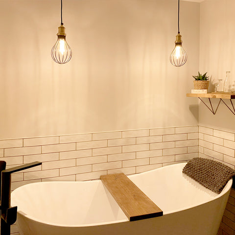 A cosy bathroom interior with tub and industrial lighting by Industville