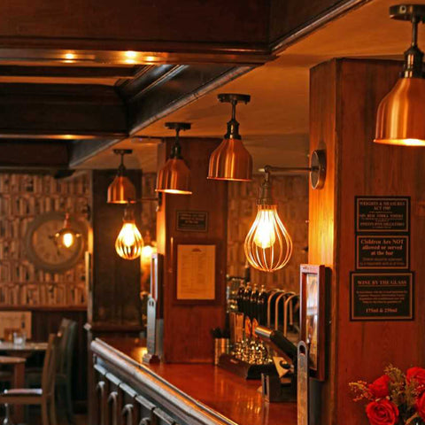 A long wooden bar with hanging cage lights