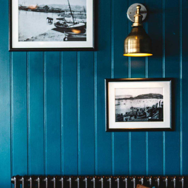 A blue restaurant wall with brass industrial light by Industville