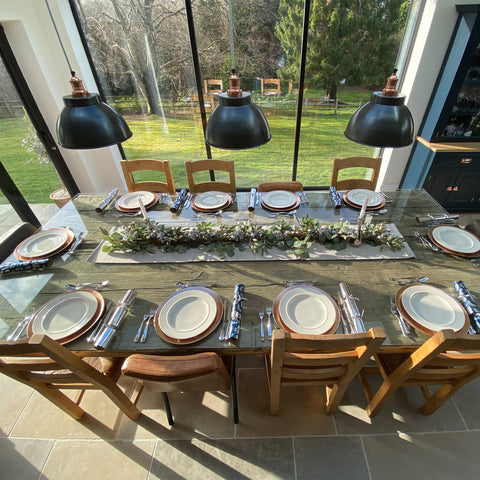 A wooden Christmas dinner table with decorations and metal lights