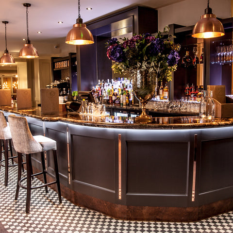 a wooden luxury bar with under lighting and hanging lights