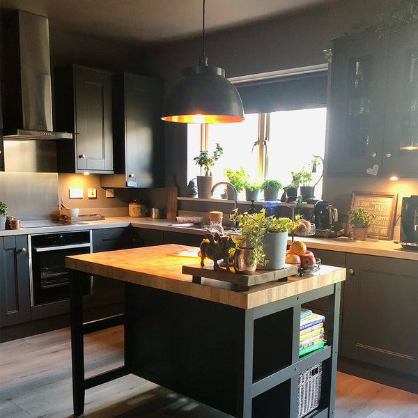 A warm kitchen interior with hanging industrial lights by Industville