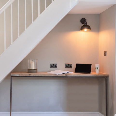 A home office desk underneath white stairs with lighting by Industville