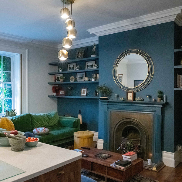 A maximalist living room interior with hanging industrial lights