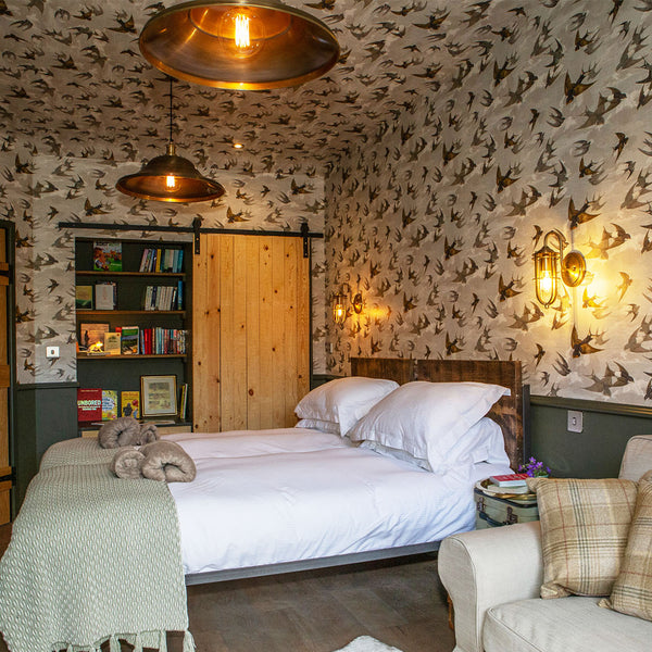 A traditional bedroom with bird wallpaper and large industrial lights