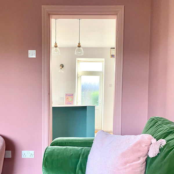 A pink minimalist living room interior with green sofa