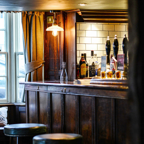 A traditional bar interior with wooden counters and stools