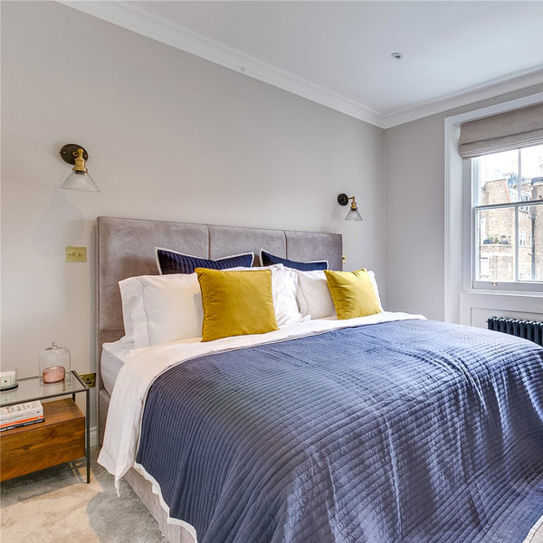 A bedroom with grey blankets and yellow pillows