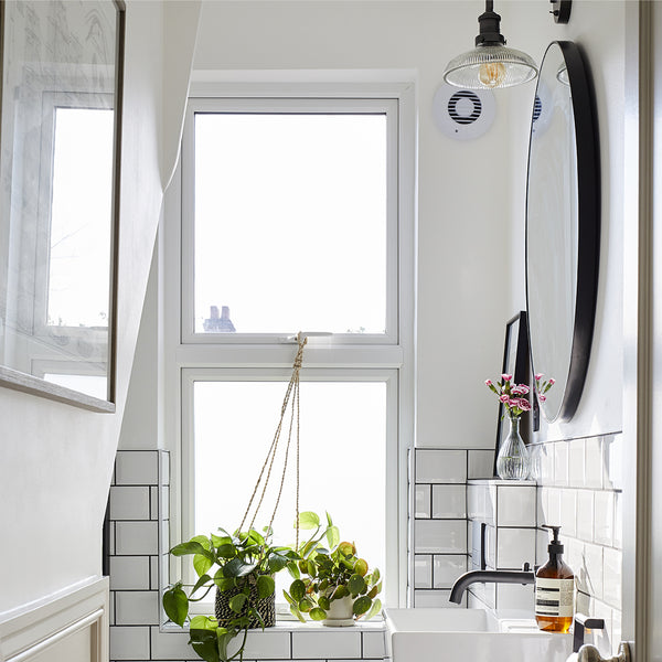 White bathroom interior with tiles, houseplants and industrial vintage lights