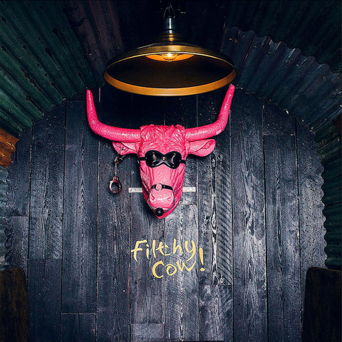 a bright pink cow head ornament in a dark bar interior