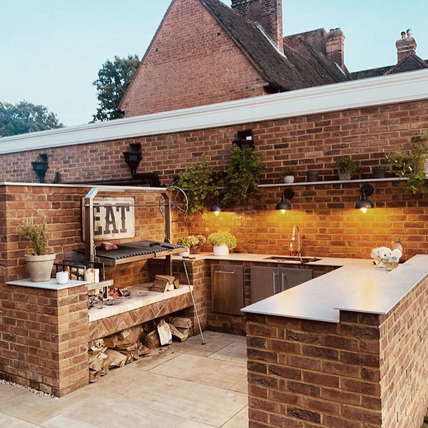 A modern outdoor kitchen with industrial style lighting