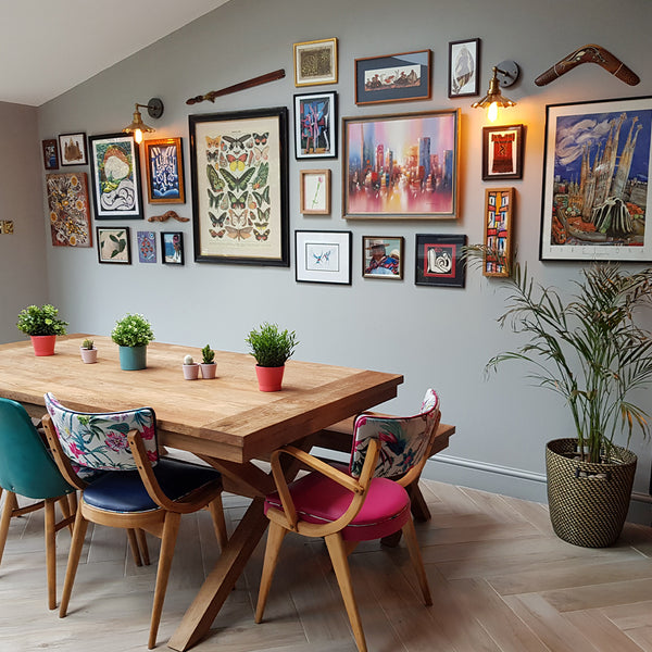 A colourful dining room with hanging pictures and metal lighting