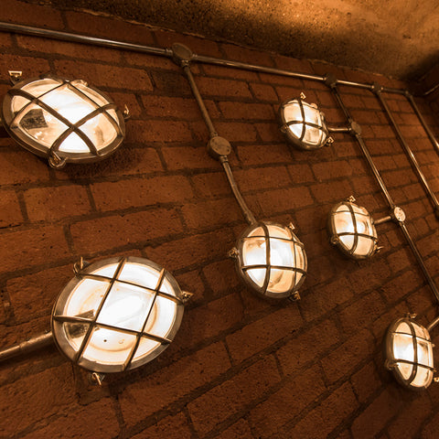 Multiple lights on a brick wall connected by pipes