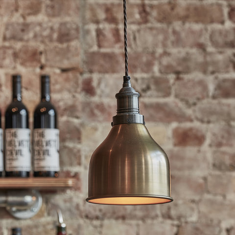 A brass industrial light by Industville with an exposed brick wall