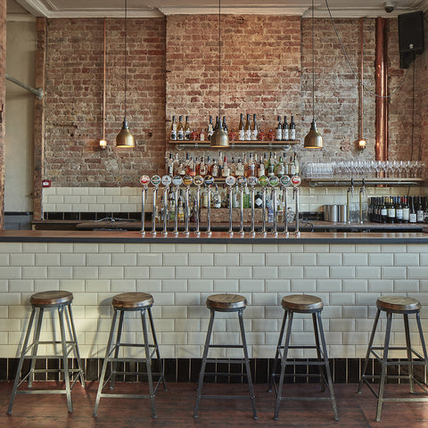 A simple bar interior with tiles, stools and brick wall