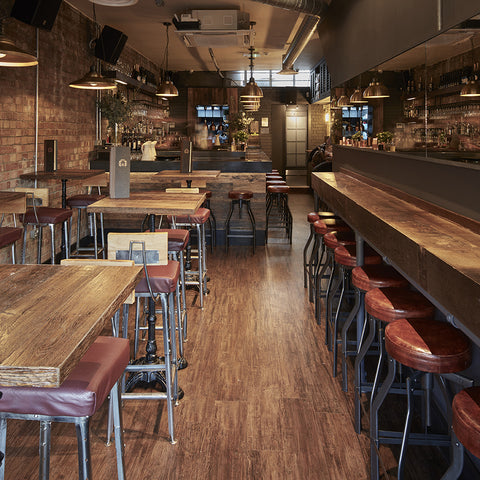 a long wooden bar with leather stools and metal lights