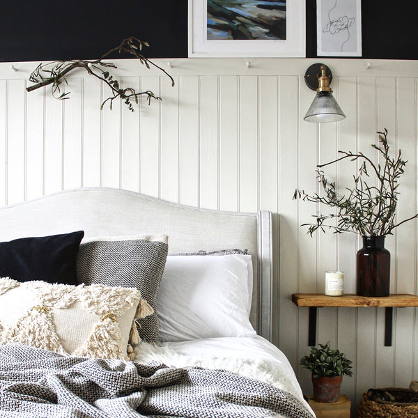 Bed with cushions on with bedside table