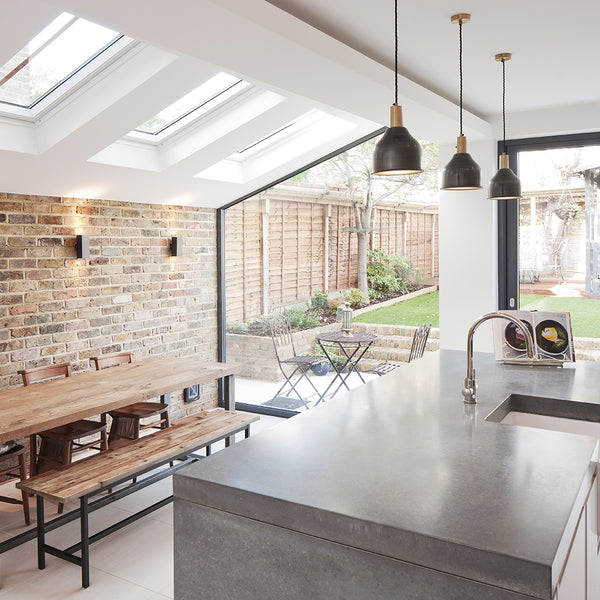 white coloured kitchen with exposed brickwork, hanging light fixtures in line with interior lighting trends