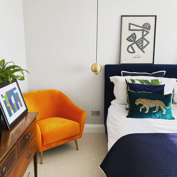 A colourful bedroom with prints and metal hanging side light