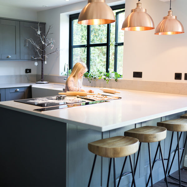 Child baking on work surface under shining brass lights