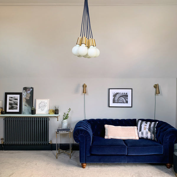 A living room with velvet sofa and hanging industrial lights