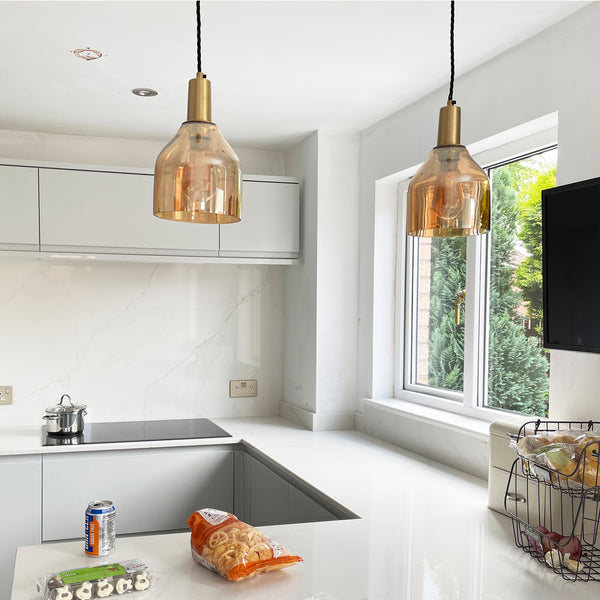 Two amber glass pendants hanging over a kitchen island