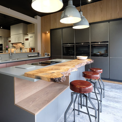 A modern kitchen with rustic wooden counter and leather stools by Industville