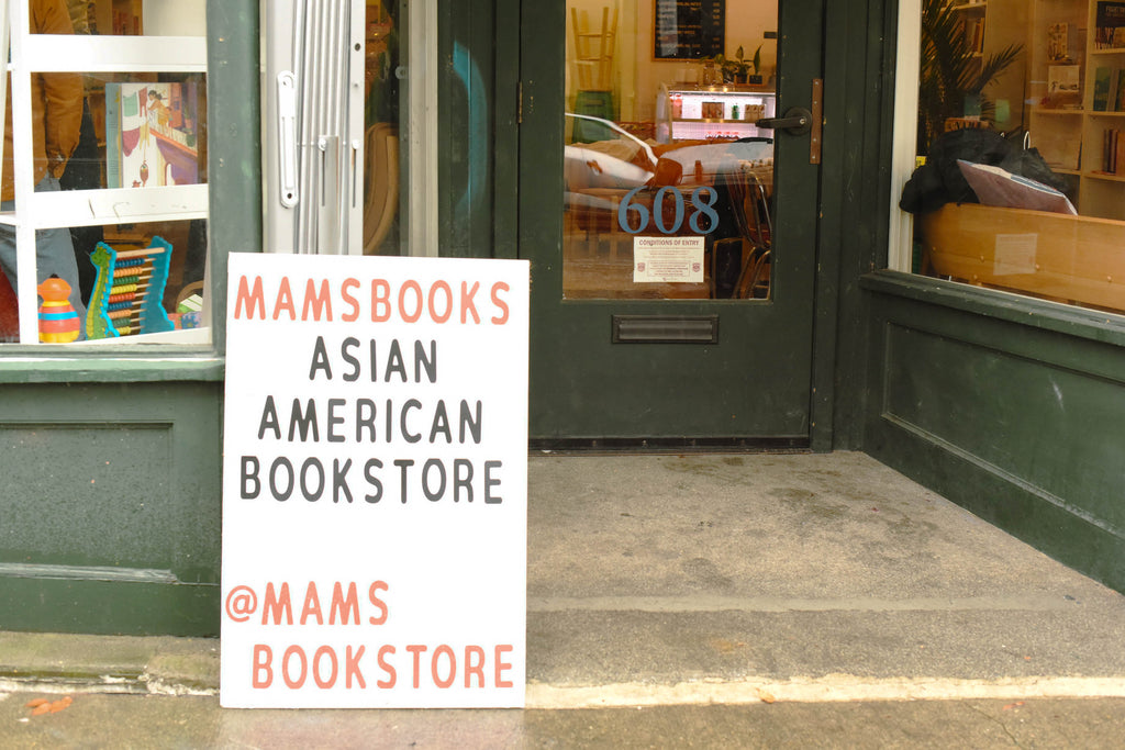 The front exterior entrance of Mam's Bookstore with signage sitting out front.
