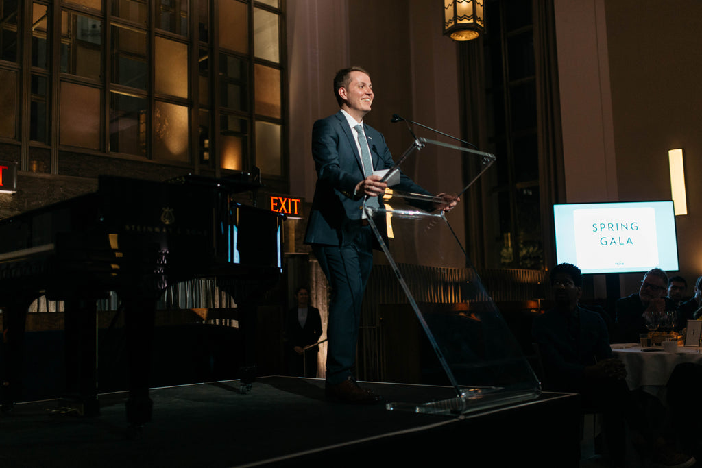 Founder of nonprofit Rethink Food, Jozwiak, stands at a podium before a large crowd at an event for Rethink Food.