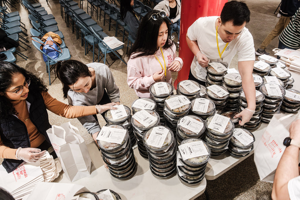 Meals for Unity team getting ready for an event with piles of packaged meals on a table in front of them.