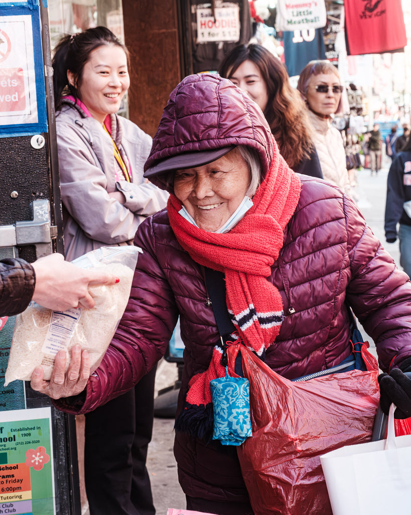 Elderly Asian woman receiving a food distribution.