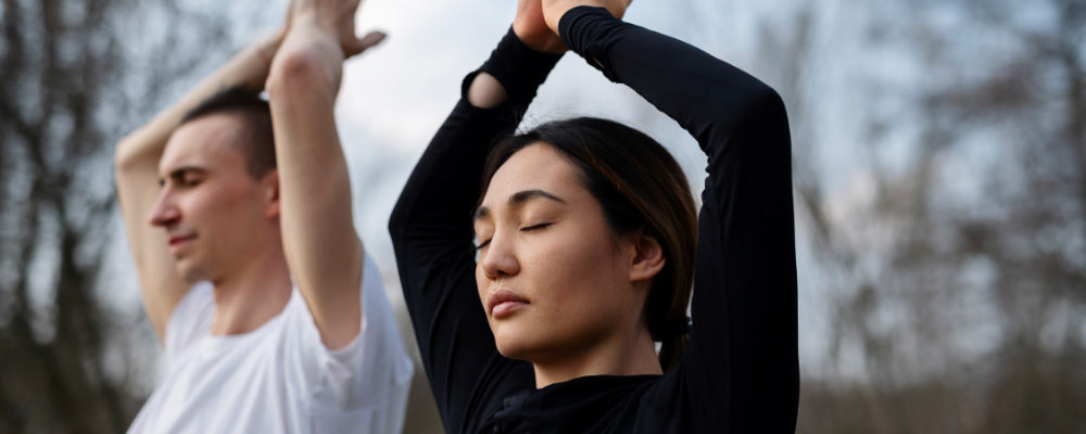 Man and woman doing a yoga pose with eyes closed