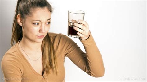 girl looking skeptically at a glass of diet soda