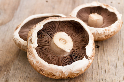 A close up of three portobello mushrooms on a wooden table